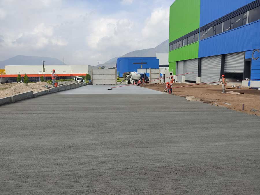 Construcción de pavimento de concreto por CCM para el Parque Sur en Panamá. Trabajadores vaciando y nivelando el hormigón frente a las bodegas.