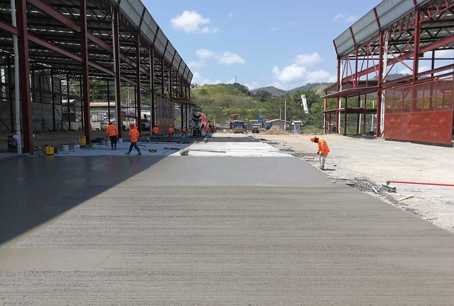 Piso de hormigón industrial en proceso de fraguado para galera de Grupo Metales en Milla 9, Panamá. Equipo de CCM nivelando el concreto.