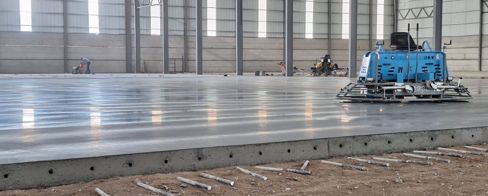 Acabado de piso industrial de concreto con allanadora mecánica en las Bodegas de Cuenca, Guatemala. Superficie de alta planitud.