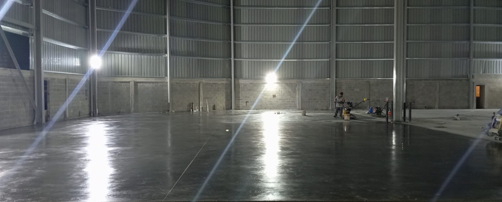 Piso industrial de concreto pulido con acabado tipo espejo en Novodepósitos SAS, República Dominicana. Maquinaria de acabado y lustrado.