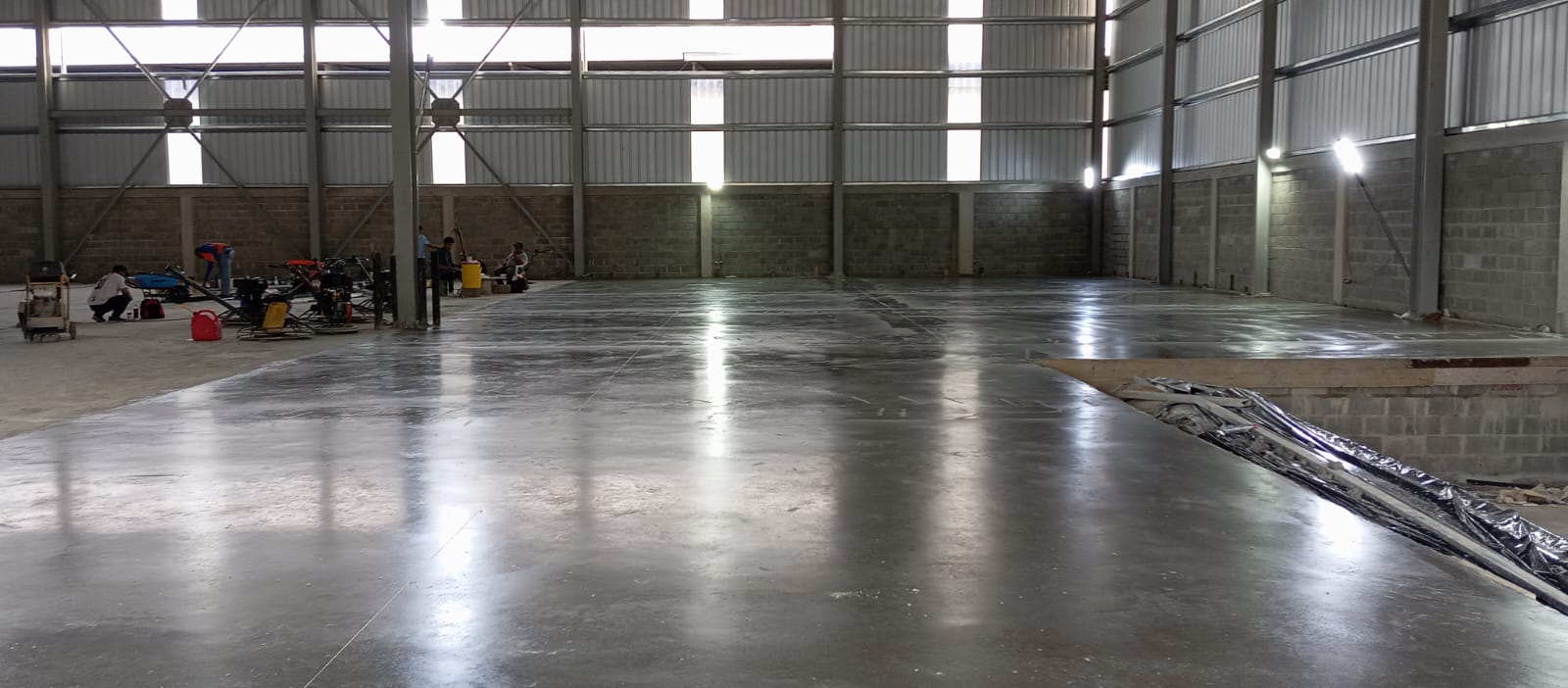 Piso industrial de concreto con acabado pulido y brillante en Novodepósitos, República Dominicana. Maquinaria de acabado en proceso.