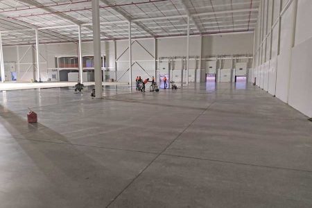 Interior de bodega industrial con piso de concreto pulido recién limpiado después de la construcción. Servicio de limpieza post-construcción de CCM.