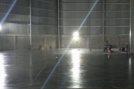 Piso industrial de concreto pulido con acabado tipo espejo en Novodepósitos SAS, República Dominicana. Maquinaria de acabado y lustrado.